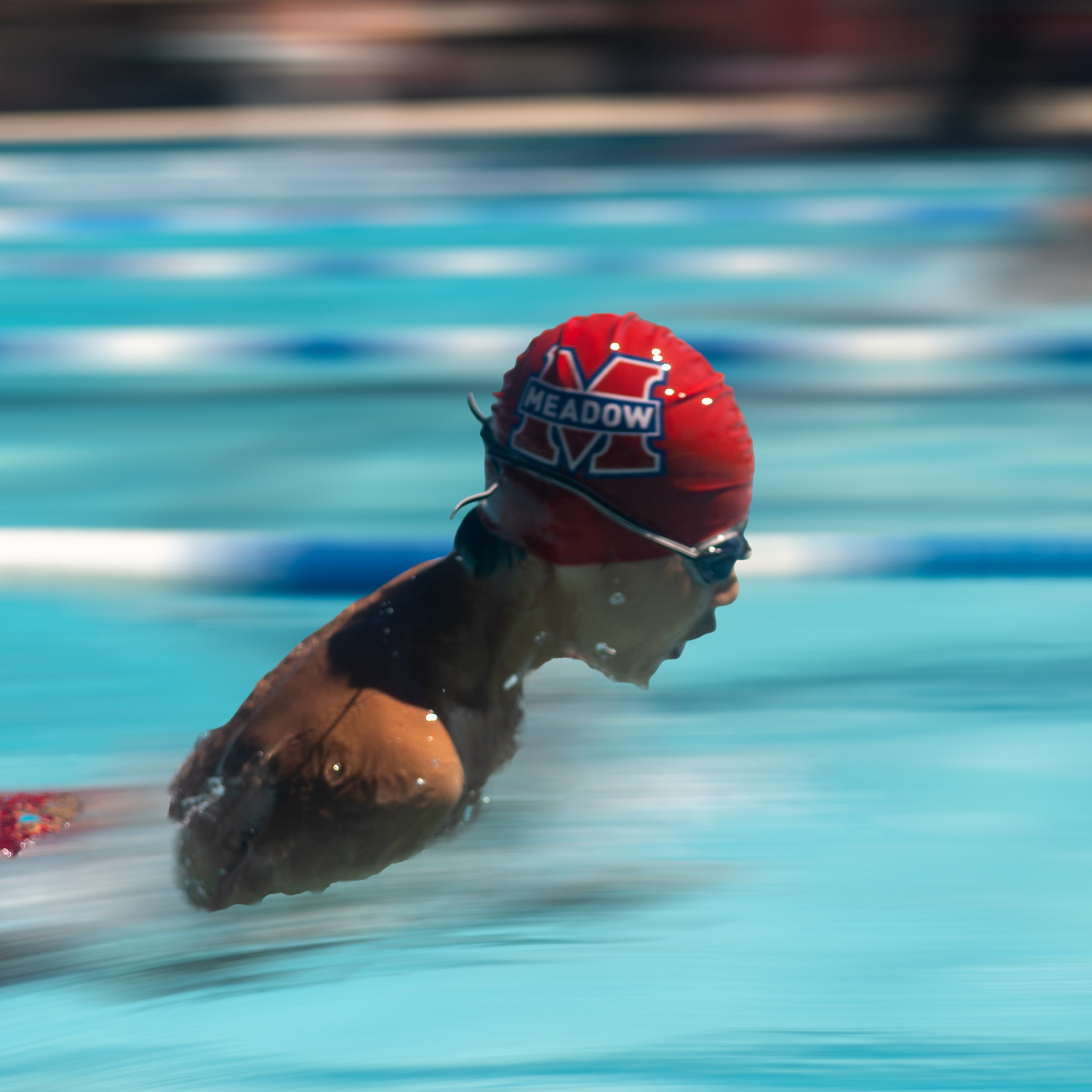 Panning blur of a swimmer in a red Meadow cap