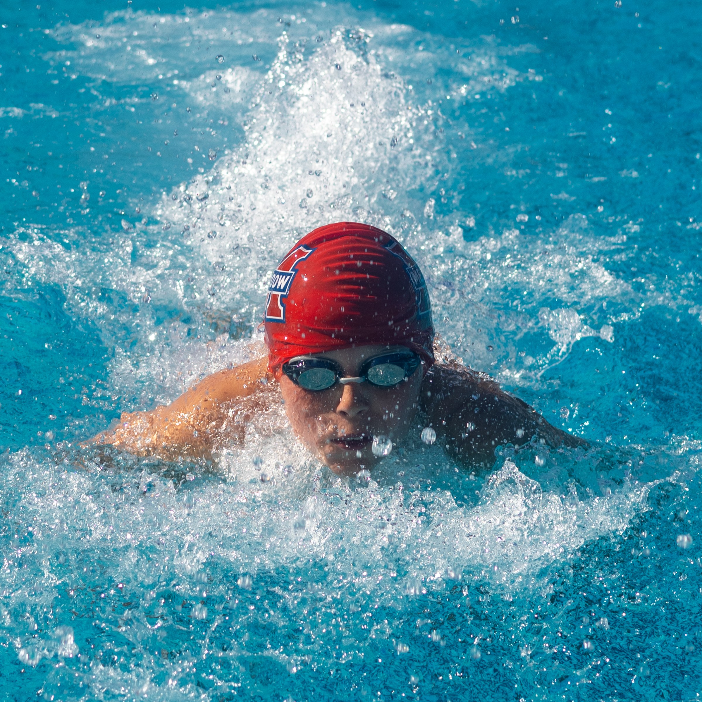 Butterfly swimmer surfacing head-on through the spray